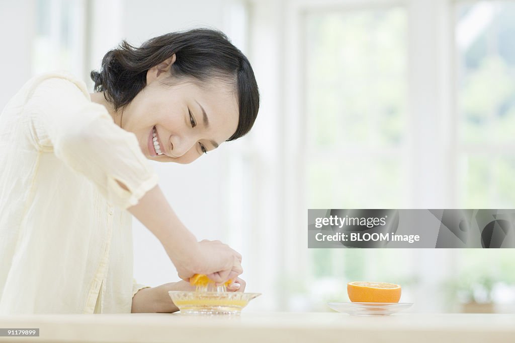 Young woman squeezing orange