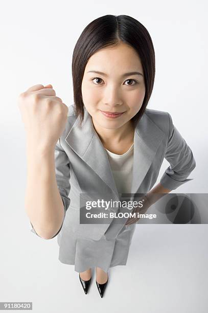 businesswoman clenching fist, portrait, high angle view, studio shot - faust in die luft stoßen stock-fotos und bilder