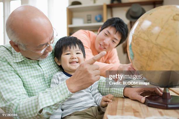 multi-generation family pointing at globe - desktop globe stock pictures, royalty-free photos & images