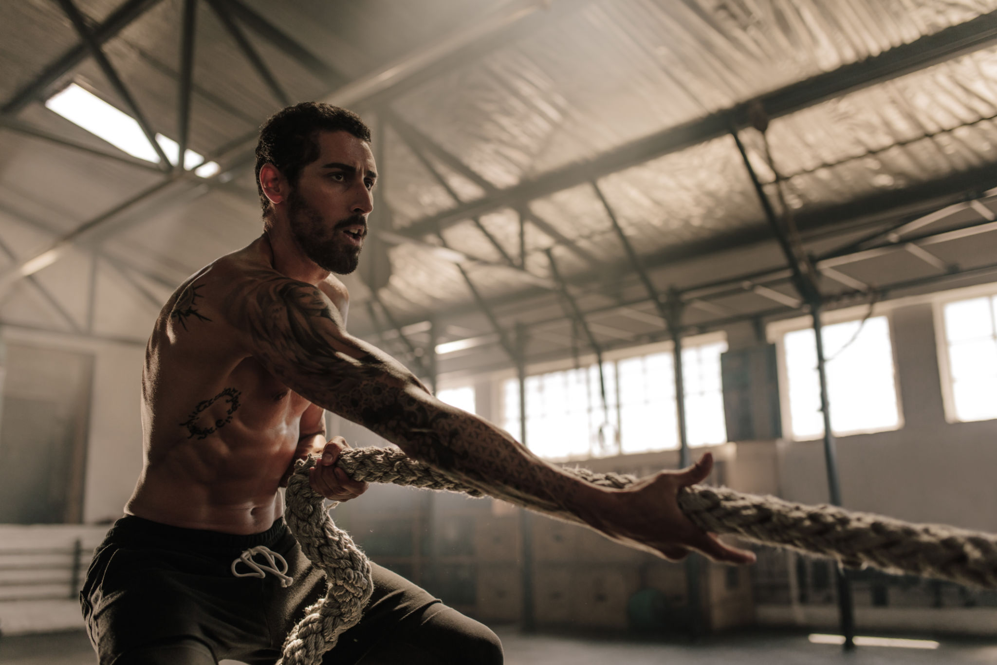 Strong man pulling heavy rope at gym Strong man pulling heavy rope at gym