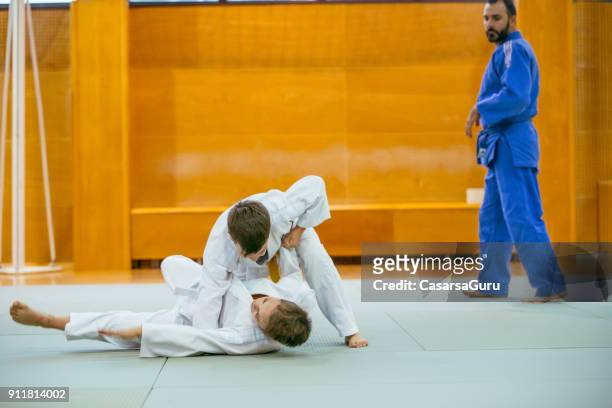 two boys practicing judo with their instructor - child judo stock pictures, royalty-free photos & images