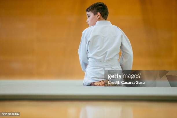 rear view of young judoist kneeling - child judo stock pictures, royalty-free photos & images