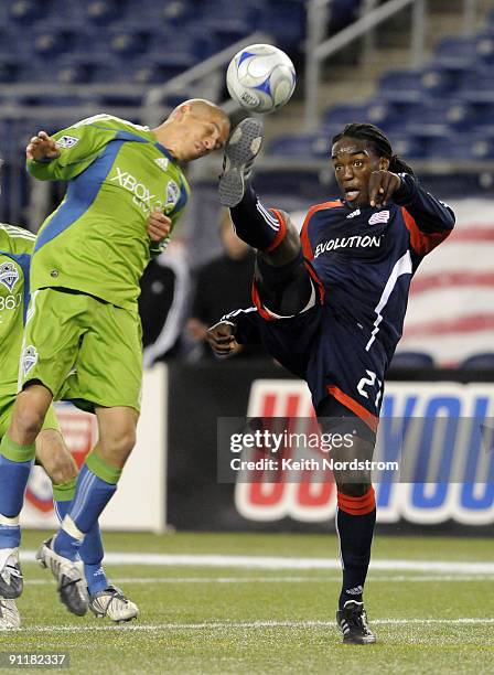 Shalrie Joseph of the New England Revolution kicks the ball in front of Osvaldo Alonso of the Seattle Sounders FC during a MLS match on September 26,...