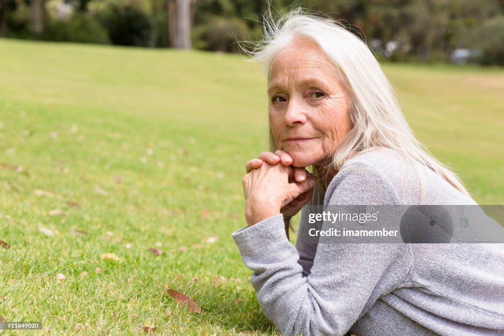 Beautiful mature woman dreaming in the park, copy space