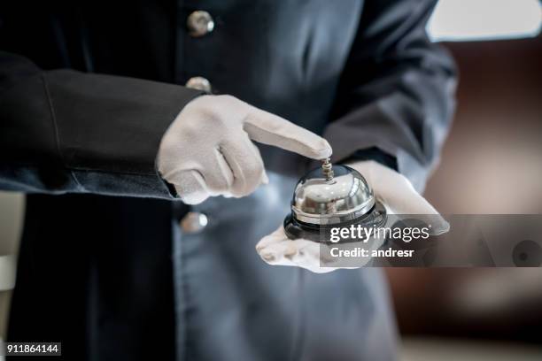 close up van onherkenbaar bell boy in een hotel rinkelen de bel - piccolo stockfoto's en -beelden