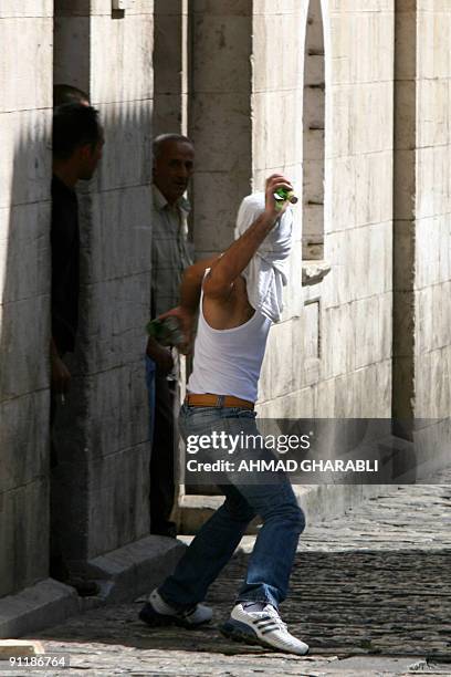 Masked Palestinian youth throws a glass bottle at Israeli policemen in Jerusalem's Old City following scuffles in the Al-Aqsa mosque compound on...