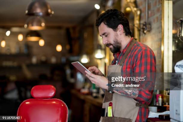 male hairstylist using a tablet computer at a barber shop - salon owner stock pictures, royalty-free photos & images
