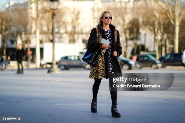 Guest wears sunglasses, a leopard print coat with fur, a flower print black and white dress, outside Chanel, during Paris Fashion Week -Haute Couture...