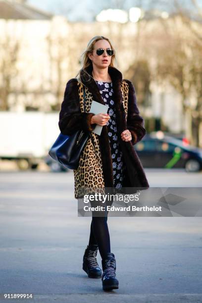 Guest wears sunglasses, a leopard print coat with fur, a flower print black and white dress, outside Chanel, during Paris Fashion Week -Haute Couture...