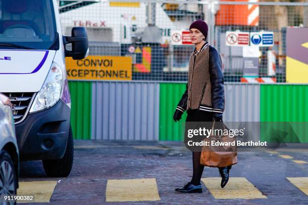Guest wears a beanie hat, a jacket with leather sleeves, a brown leather bag, black shoes, tights, outside Chanel, during Paris Fashion Week -Haute...
