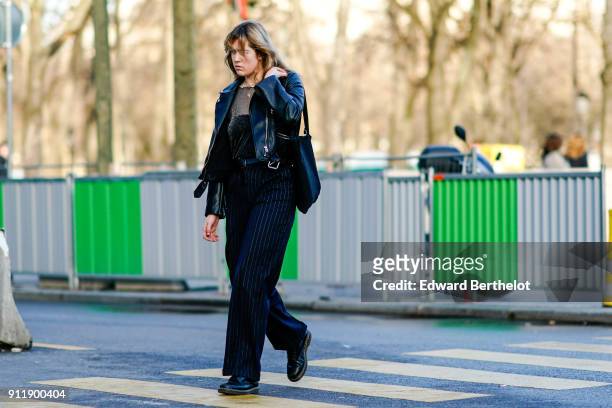Guest wears a mesh top, a black leather jacket, pants, outside Chanel, during Paris Fashion Week -Haute Couture Spring/Summer 2018, on January 23,...