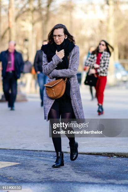 Guest wears glasses, a brown bag, a coat, a black dress, a scarf, tights, black leather shoes, outside Chanel, during Paris Fashion Week -Haute...