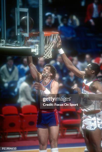 Kelly Tripucka of the Detroit Pistons goes in for a layup in front of Rick Mahorn of the Washington Bullets during an NBA basketball game circa 1983...