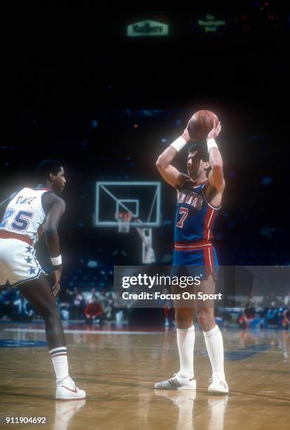 Kelly Tripucka of the Detroit Pistons looks to pass the ball over Darren Daye of the Washington Bullets during an NBA basketball game circa 1984 at...