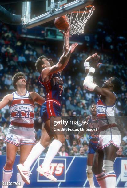 Kelly Tripucka of the Detroit Pistons goes up for a layup over Dan Roundfield of the Washington Bullets during an NBA basketball game circa 1986 at...