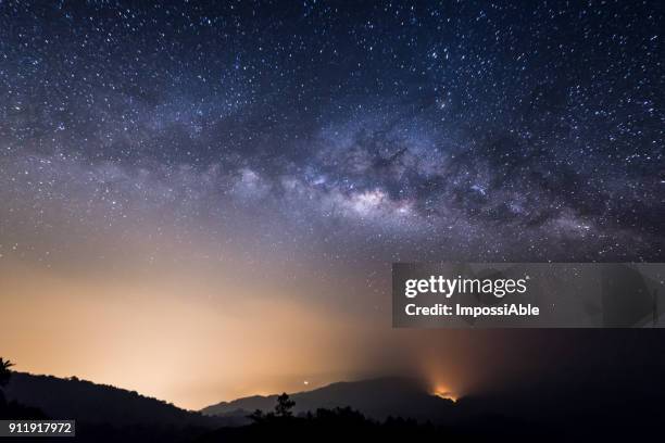 milky way galaxy across the night sky with the city lights and the mountain below - impossiable fotografías e imágenes de stock