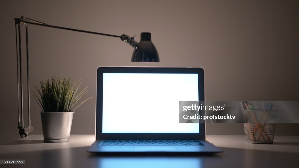 Laptop mit einem weißen Bildschirm auf dem Tisch in der Nacht