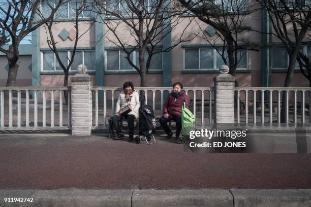 This photo taken on January 15, 2018 shows two women sitting beside a road in "Abai village", a settlement originally created by North Korean...