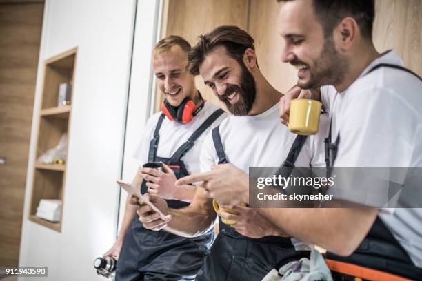 team der glückliche arbeiter mit smartphone auf eine kaffeepause. - handwerker stock-fotos und bilder