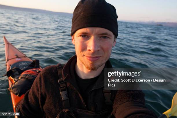 portrait of a young man in a kayak on the water at sunset, kachemak bay state park - sunset bay state park stock pictures, royalty-free photos & images