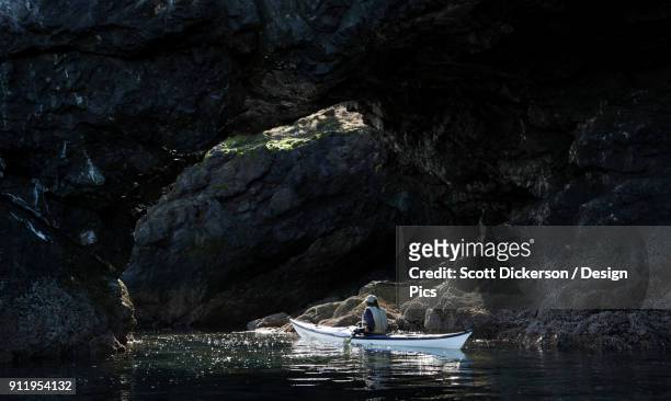 canoeing along dark rocks of the shoreline in kachemak bay state park - kachemak bay stock pictures, royalty-free photos & images