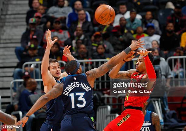 Kent Bazemore of the Atlanta Hawks passes the ball against Nemanja Bjelica and Marcus Georges-Hunt of the Minnesota Timberwolves at Philips Arena on...