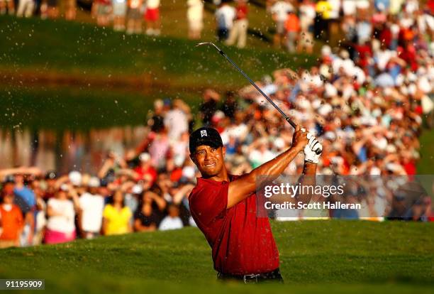 Tiger Woods plays a bunker shot on the 18th hole during the final round of THE TOUR Championship presented by Coca-Cola, the final event of the PGA...