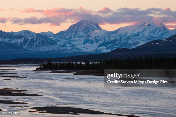 the sun sets on mt. deborah and mt. hess in the alaska range, viewed from the susitna river bridge along the denali highway - denali highway stock pictures, royalty-free photos & images