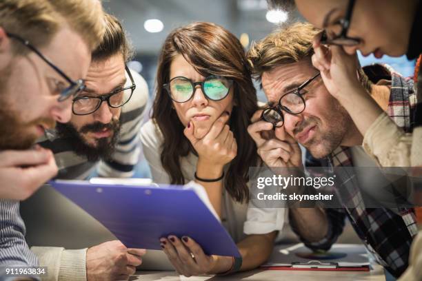 team van nerdy ondernemers lezen verwarrend verslagen in het kantoor. - verward stockfoto's en -beelden