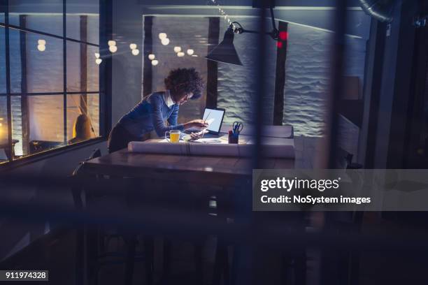 working late. young african-american woman working in office - 24 7 stock pictures, royalty-free photos & images