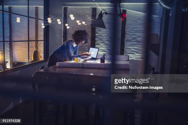 working late. young african-american woman working in office - working late imagens e fotografias de stock