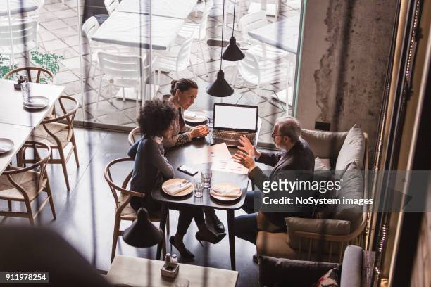 businesspeople having meeting in a restaurant. - bonding stock pictures, royalty-free photos & images