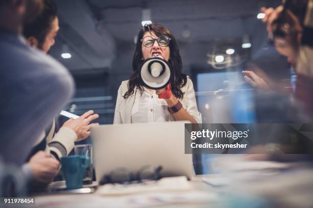 rude female leader yelling at her coworkers through megaphone in the office. - angry boss stock pictures, royalty-free photos & images