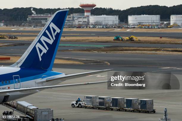 Member of the ground crew for All Nippon Airways Co. Operates a tug towing cargo containers at Narita Airport in Narita, Chiba Prefecture, Japan, on...