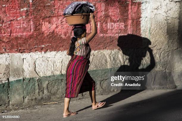 Woman carries laundry in a bucket on her head after washing it in the lake in Santiago Atitlan on Lake Atitlan, Guatemala on January 24, 2018.