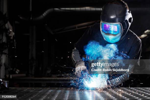 blacksmith wearing protective mask welding in workshop - fabbro ferraio foto e immagini stock