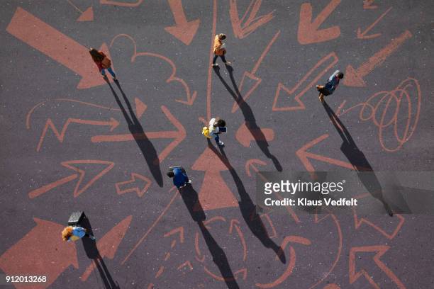 top view of people walking around on painted asphalt with arrows - wegweiser stock-fotos und bilder
