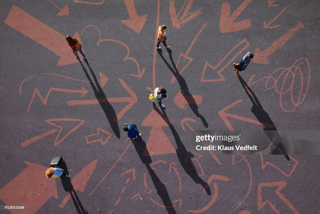 Top view of people walking around on painted asphalt with arrows