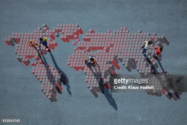top view of 3 pairs of people talking, while standing on world map, painted on asphalt - internationalisation photos et images de collection