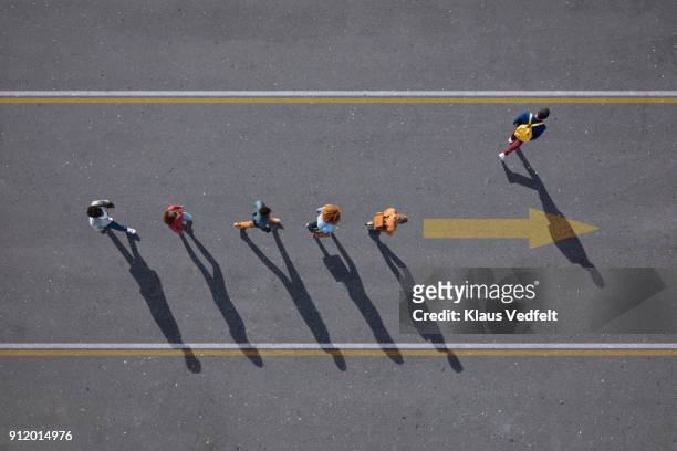people walking in line on road, painted on asphalt, one person walking off. - entscheidung stock-fotos und bilder