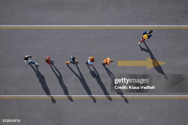 people walking in line on road, painted on asphalt, one person walking off. - sortir du rang photos et images de collection