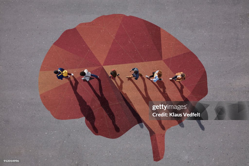 People walking in line across painted brain, on asphalt