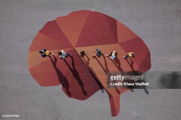 people walking in line across painted brain, on asphalt - group people thinking stock pictures, royalty-free photos & images