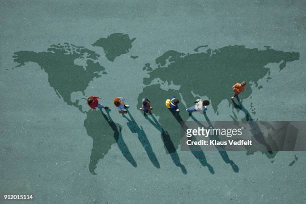 people walking in line across world map, painted on asphalt, front person walking left - world map stock-fotos und bilder