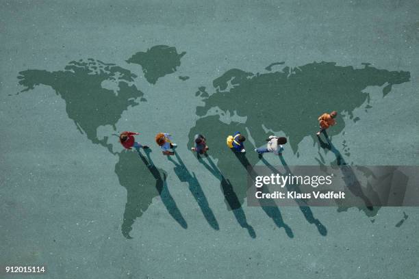 people walking in line across world map, painted on asphalt, front person walking left - africa maps photos et images de collection