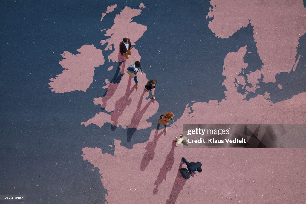 Top view of businesspeople walking out of Great Britain on painted north european map