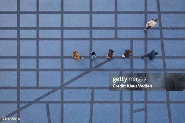 people walking in line on road, painted on asphalt, one person walking off in different direction - one direction groupe stock pictures, royalty-free photos & images