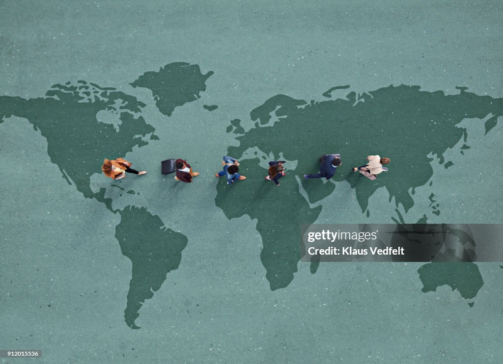 Businesspeople walking in line across world map, painted on asphalt