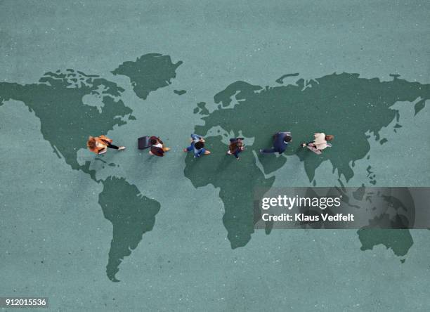 businesspeople walking in line across world map, painted on asphalt - comunicazione globale foto e immagini stock