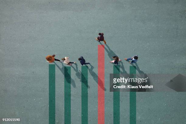 businesspeople walking in line on bar chart painted on asphalt, one person walking off. - person in education stock-fotos und bilder